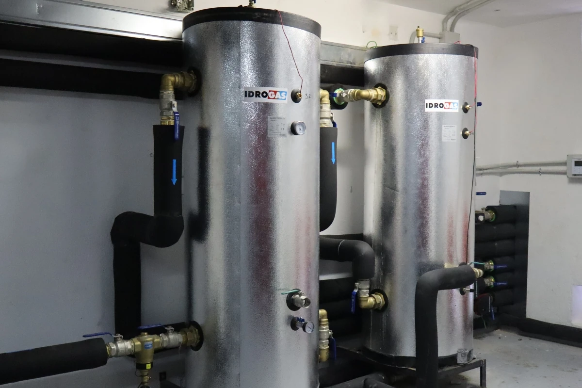 Dos depósitos verticales aislados conectados a una red de tuberías con aislamiento térmico, instalados en una sala de máquinas para la gestión y almacenamiento de energía térmica.
