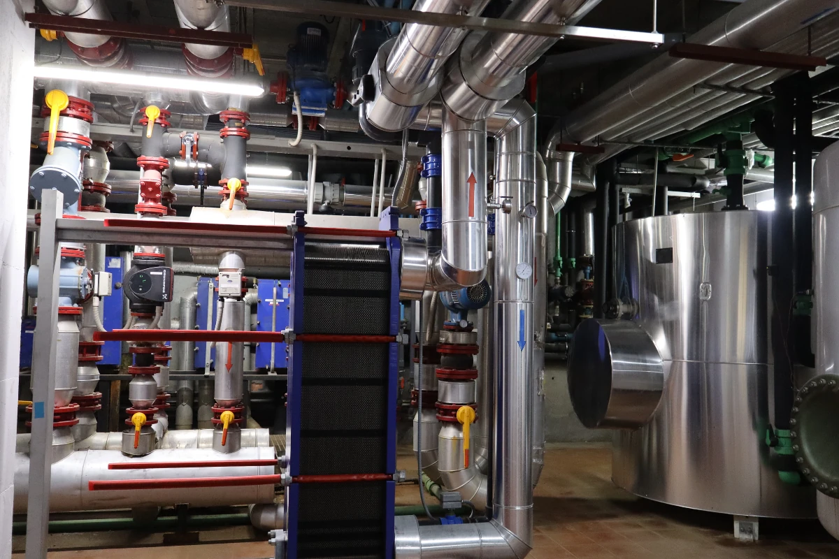 Equipo industrial de climatización o producción térmica de la marca Trane instalado en una sala técnica, con paneles de acceso frontales y conexiones a sistemas de tuberías en su entorno.