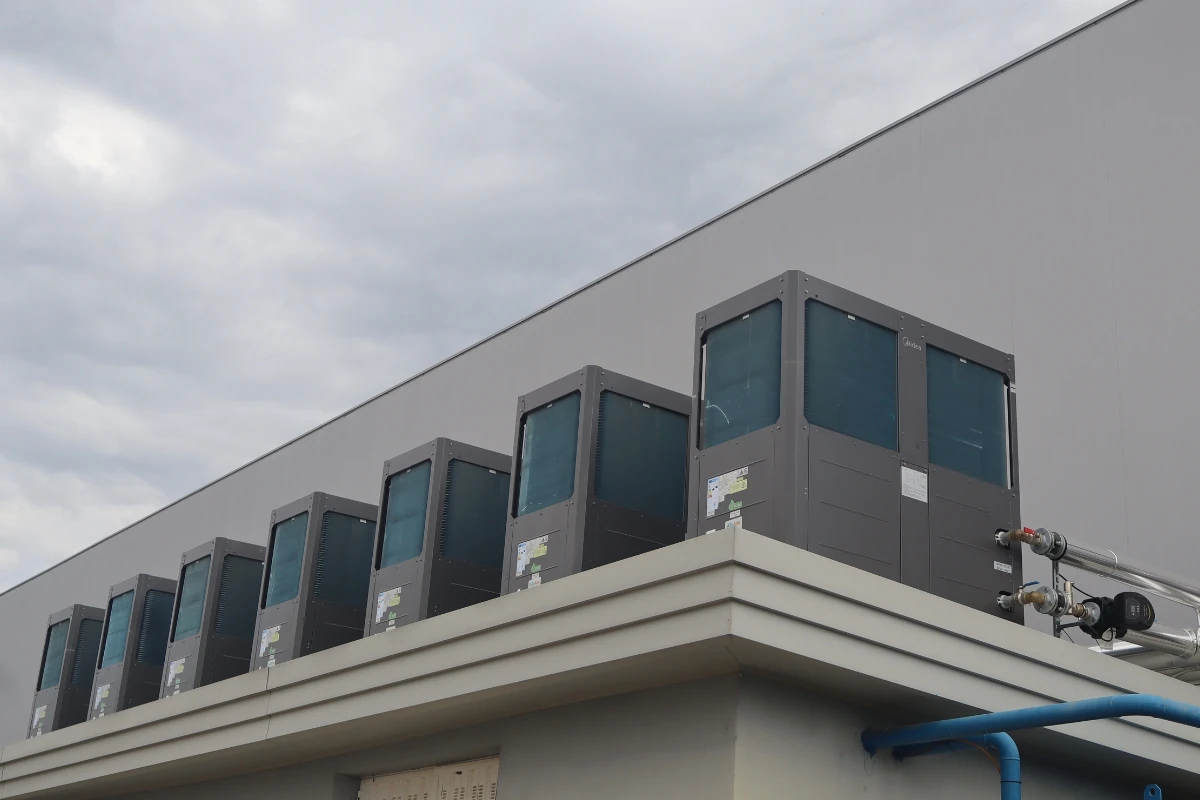 Conjunto de unidades industriales de bomba de calor o climatización instaladas en la cubierta de un edificio, conectadas mediante tuberías aisladas de gran diámetro para la distribución de energía térmica.