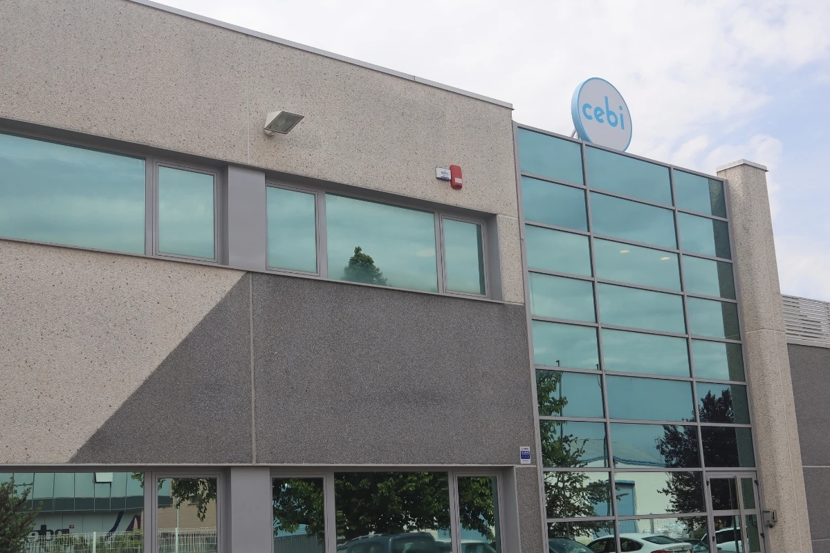 Fachada de un edificio industrial o de oficinas de la empresa Cebi, con amplias superficies acristaladas, revestimiento exterior en tonos grises y el logotipo corporativo visible en la parte superior.