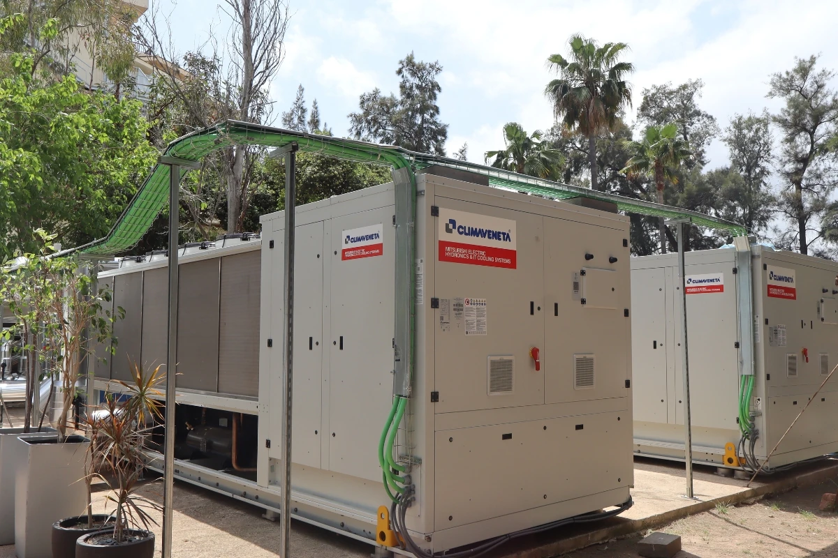 Conjunto de unidades de bomba de calor o climatización industrial conectadas mediante canalizaciones y cableado, instaladas en el exterior de un complejo hotelero.