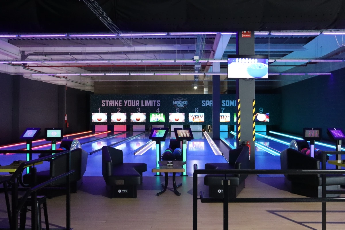 Bolera interior con varias pistas equipadas con sistemas electrónicos de puntuación, iluminación decorativa y zonas de descanso para los jugadores.