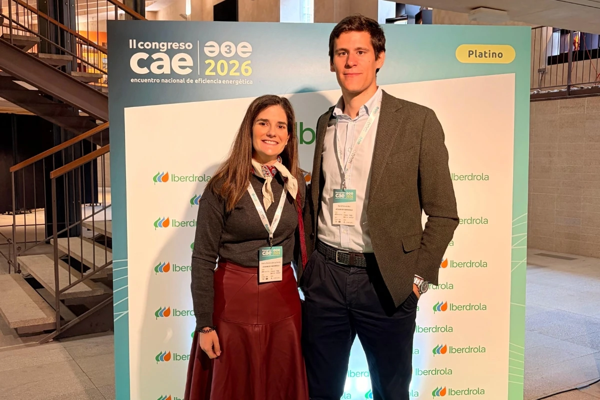 Dos asistentes posan frente a un panel corporativo durante el II Congreso CAE 2026, encuentro nacional de eficiencia energética. Al fondo se observan los logotipos de Iberdrola y la identificación del evento.
